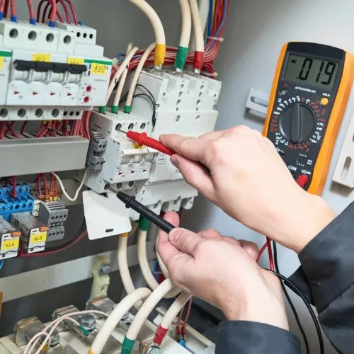 Électricien mesurant une tension avec un multimètre sur un tableau électrique